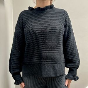 Madewell crew neck black sweater with ruffles around the neck and sleeves